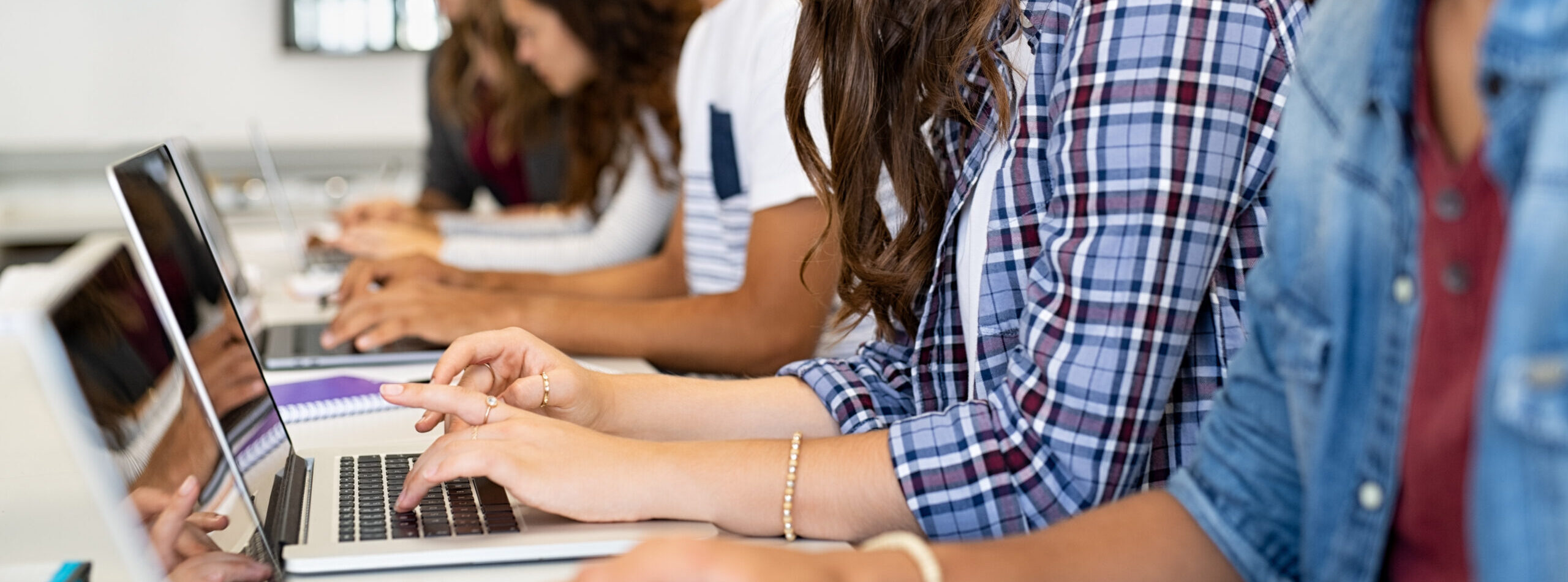 Group of high school students using laptop in classroom